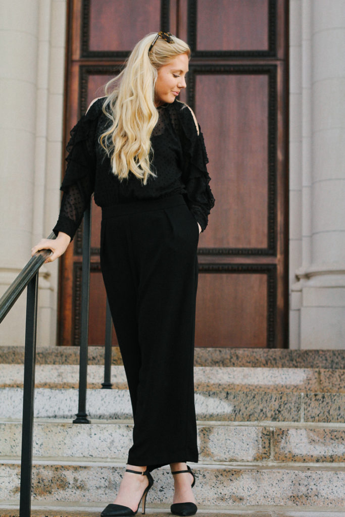 dressed up in a black cold shoulder jumpsuit with statement earrings