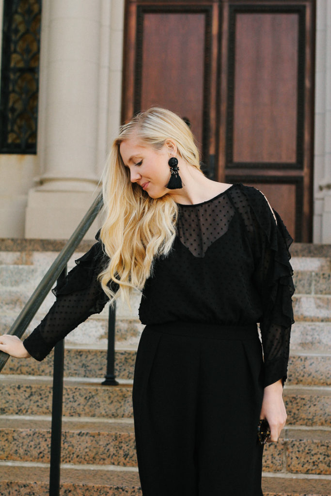 Dressed up in a black cold shoulder jumpsuit with statement earrings